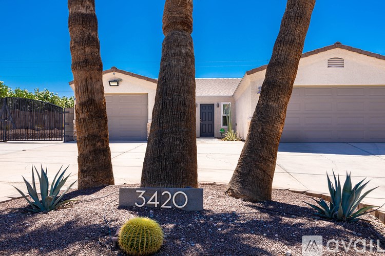 A cactus sits in front of a house with the number 3420 on a stone sign.