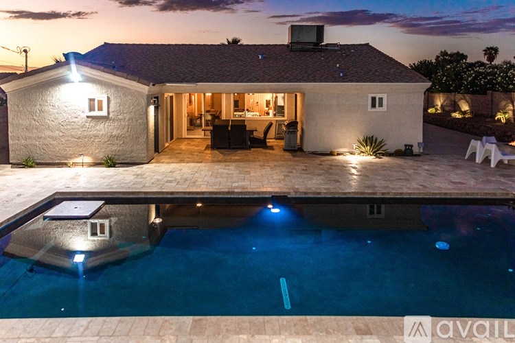 A house with a pool in front of it at night.