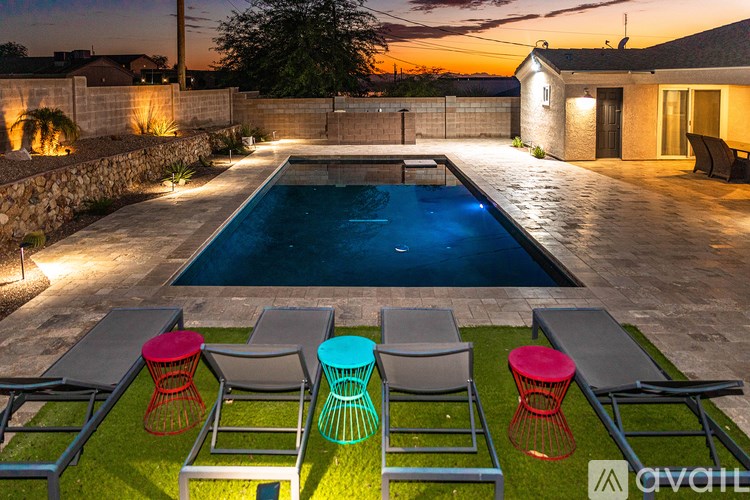 A backyard with a pool and four chairs.