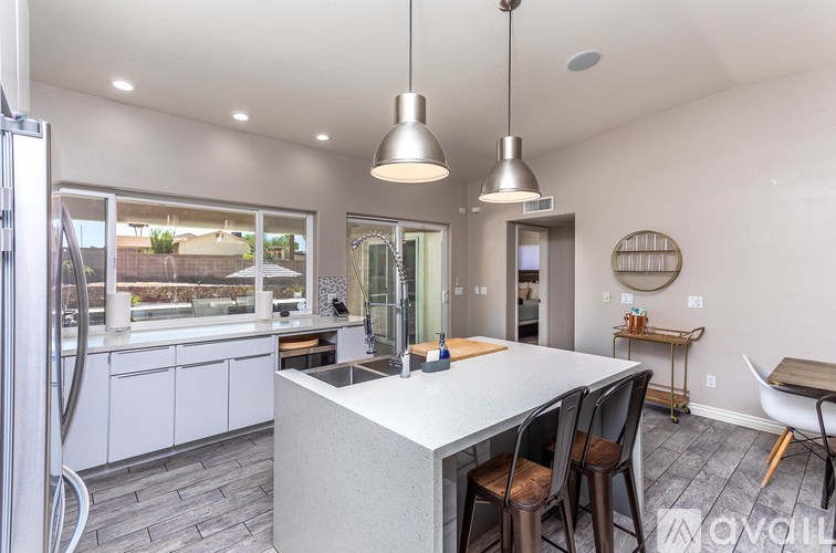 A modern kitchen with a large island and pendant lights.