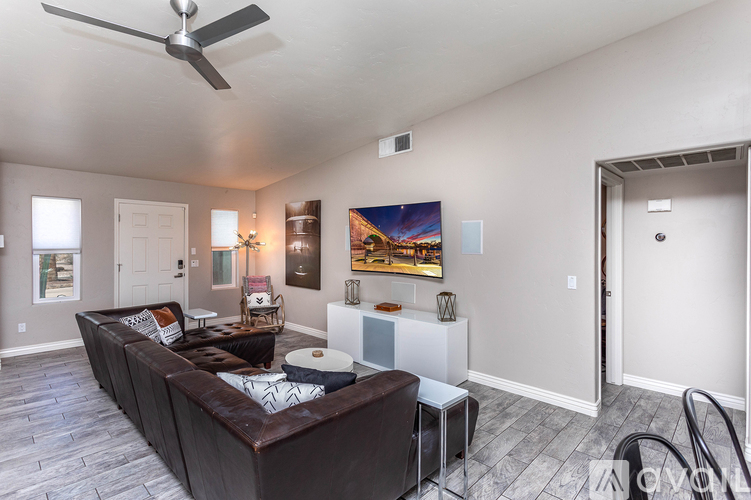A living room with a brown couch and a ceiling fan.