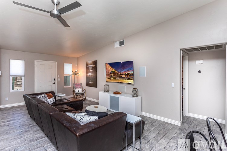 A living room with a brown couch and a ceiling fan.