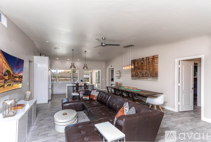 A living room with a brown couch and a painting on the wall.