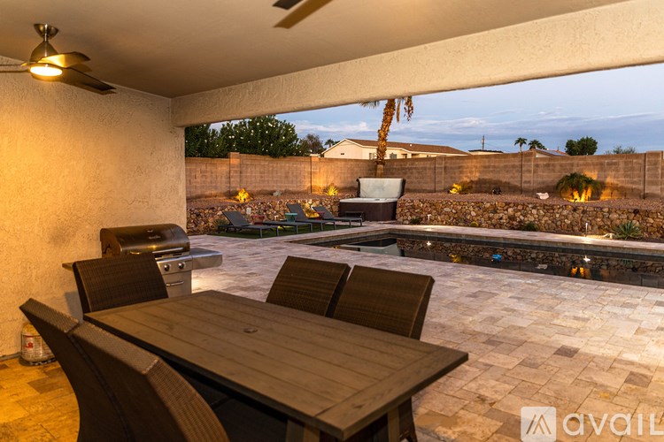 A patio with a table and chairs overlooking a pool.