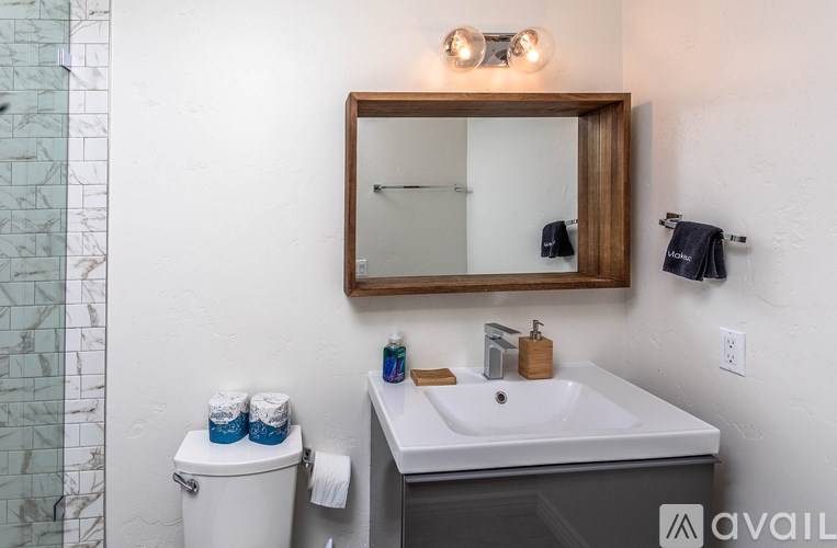 A bathroom with a toilet, sink, mirror and towel rack.