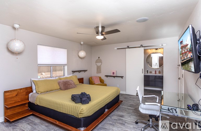 A bedroom with a bed, chair, and a television.