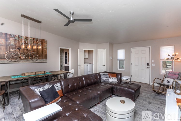 A living room with a brown leather couch and a fan on the ceiling.