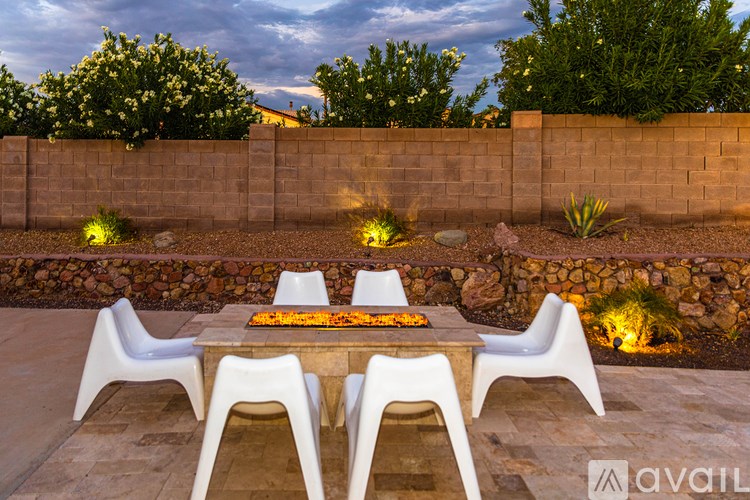A table with chairs and a fire pit in the middle of a patio.
