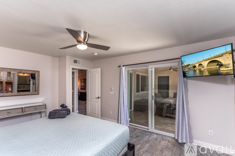 A bedroom with a bed, a ceiling fan, and a television displaying a bridge.