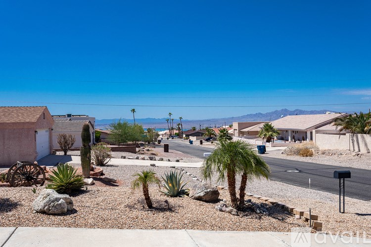 A desert landscape with a few palm trees and a house in the background.