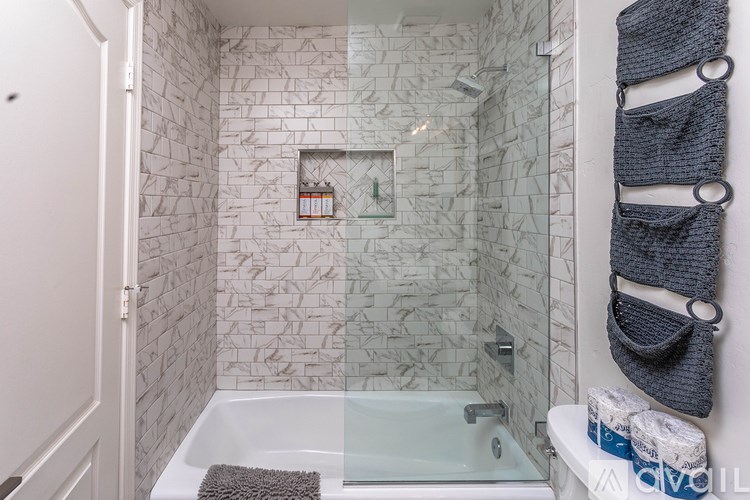 A bathroom with a white tub and a glass shower door.
