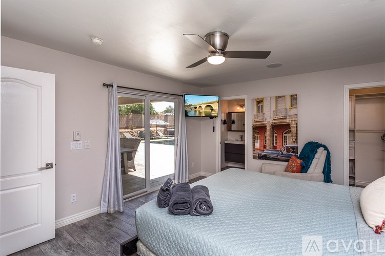 A bedroom with a bed, a ceiling fan, and a sliding glass door leading to a balcony.