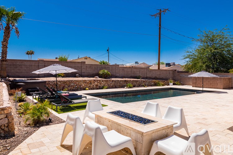 A poolside table with chairs and umbrellas overlooking a pool.
