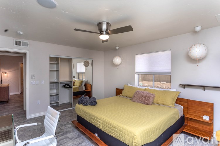 A bedroom with a bed, chair, and ceiling fan.