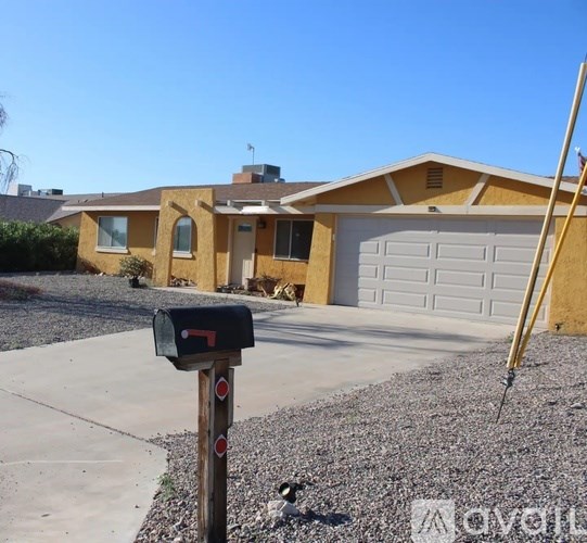A yellow house with a black mailbox in front.