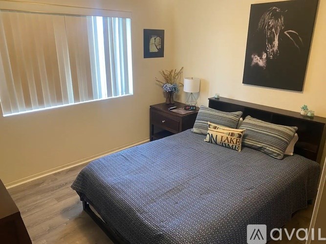 A bedroom with a bed, nightstand, and a window with blinds.