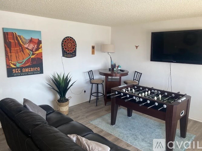 A living room with a foosball table and a poster of a canyon.