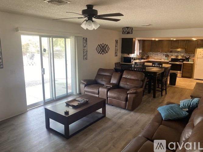 A living room with brown leather furniture and a ceiling fan.