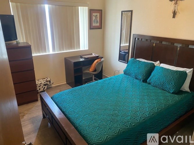 A bedroom with a bed, desk, and chair.