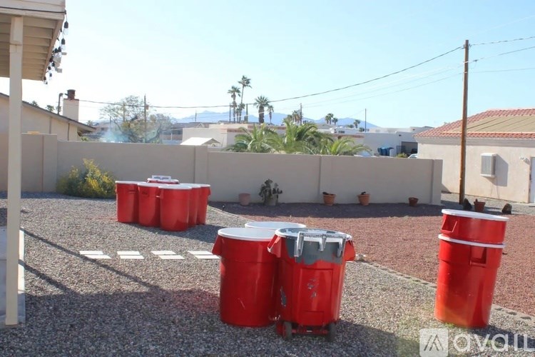 A gravel area with red bins and a white bin with a silver lid.