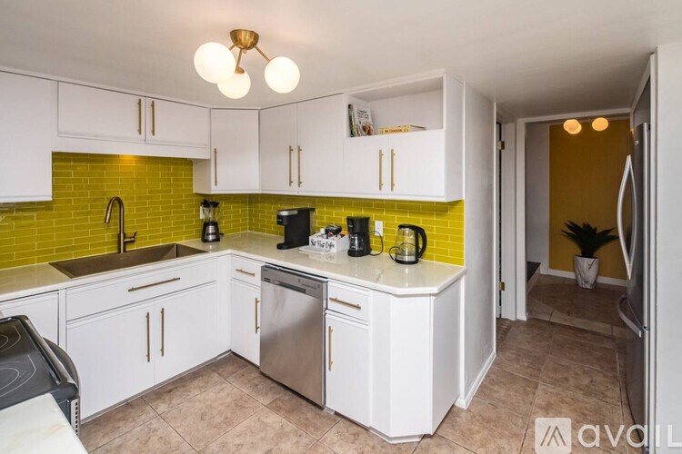 A kitchen with white cabinets and a green backsplash.