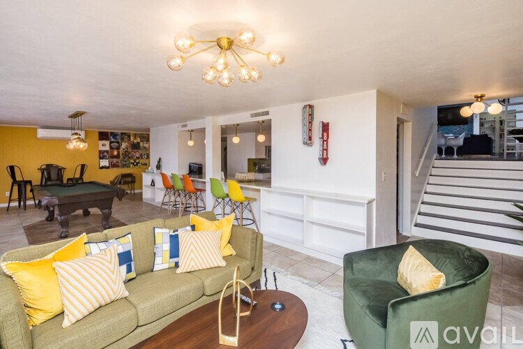 A living room with a green couch and yellow pillows.