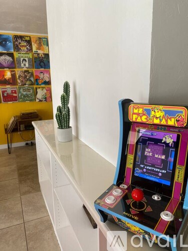A Pac-Man arcade game machine sits on a white shelf.