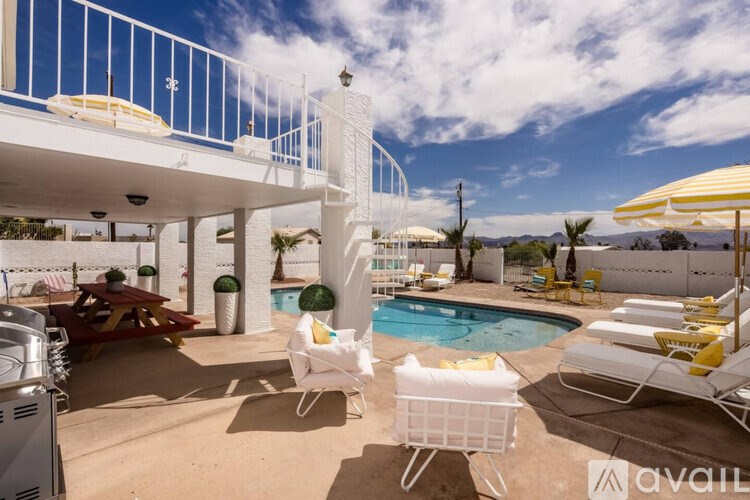A poolside area with sun loungers and a white building.