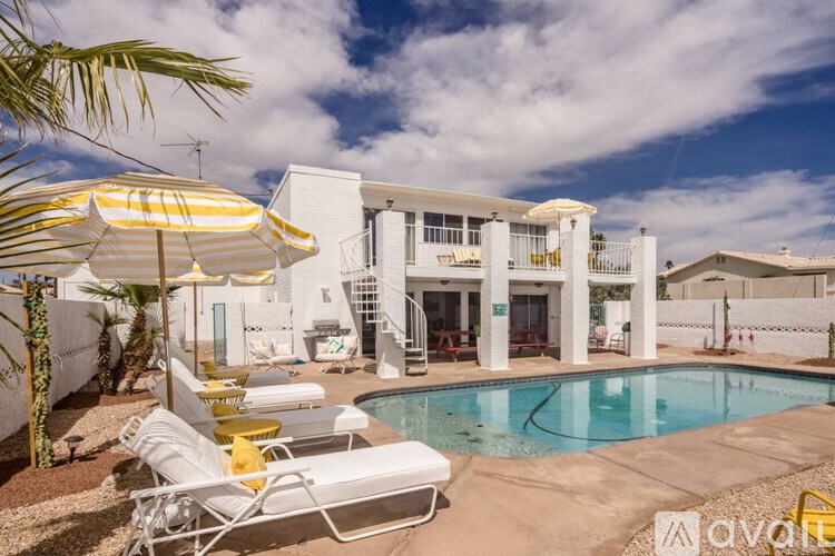 A white house with a pool and sun loungers.