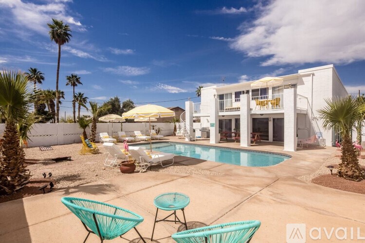 A sunny day at a poolside with a white building in the background.
