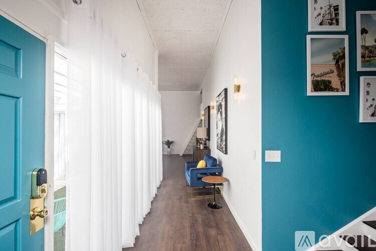 A long hallway with a blue door and white walls.