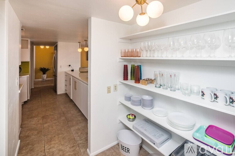 A kitchen with a white shelf holding glasses and plates.