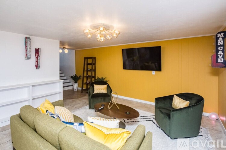 A living room with a green couch and a yellow cushion.