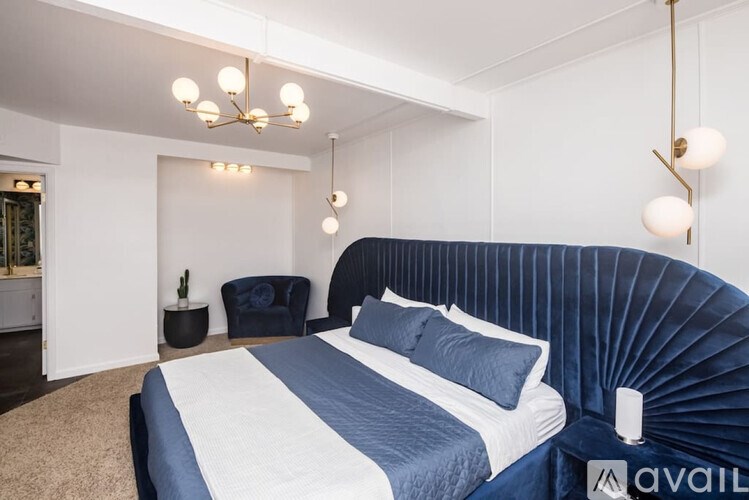 A bedroom with a large bed and a blue velvet headboard.