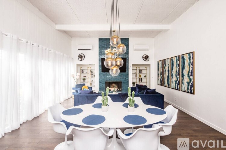 A modern dining room with a white table and blue polka dot tablecloth.