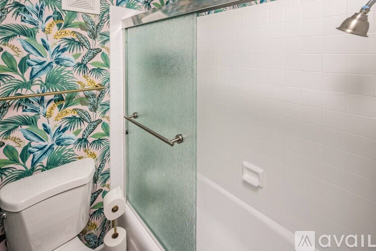 A bathroom with a glass shower door and a toilet paper roll on the toilet.