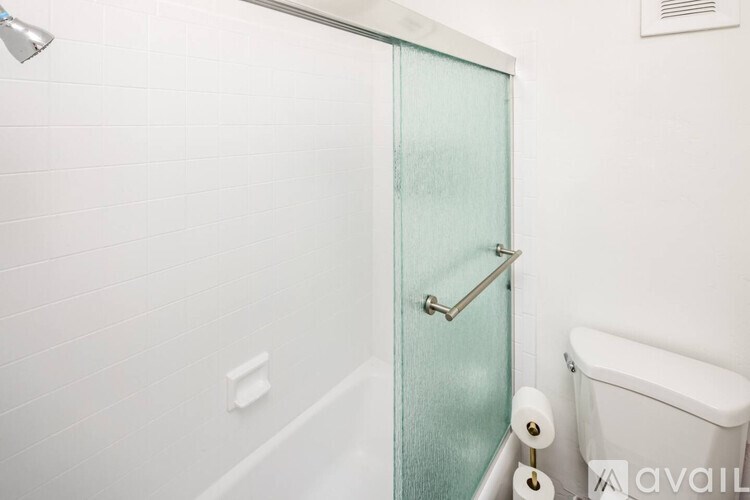 A white bathroom with a glass door and a white tub.
