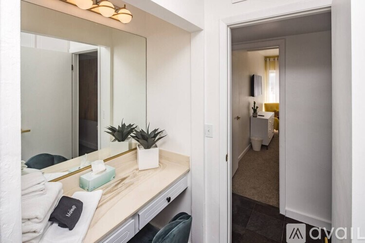 A bathroom with a mirror, towel, and a plant on the counter.