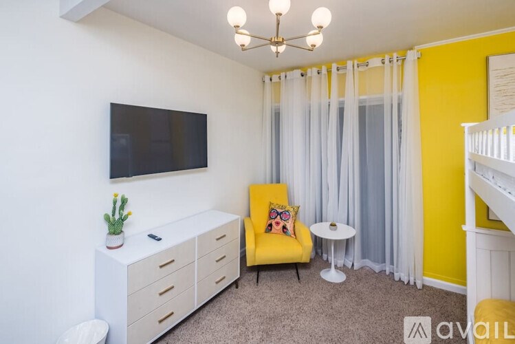A living room with a yellow chair and a white cabinet.