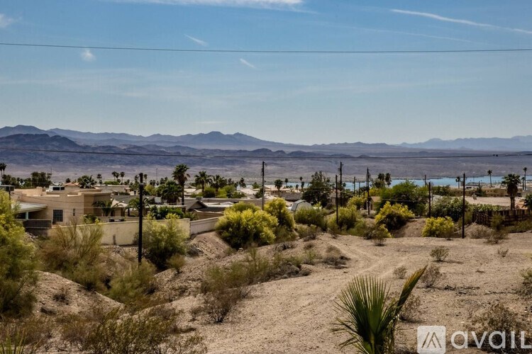 A desert landscape with a few houses and mountains in the distance.