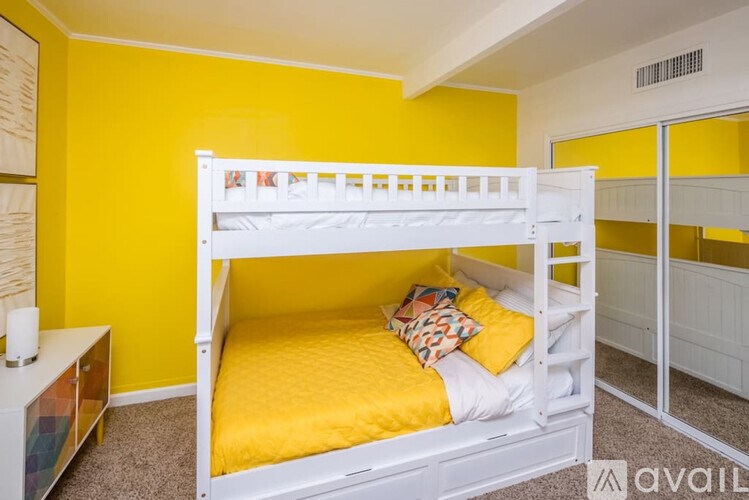 A white bunk bed with a yellow mattress in a room with yellow walls.