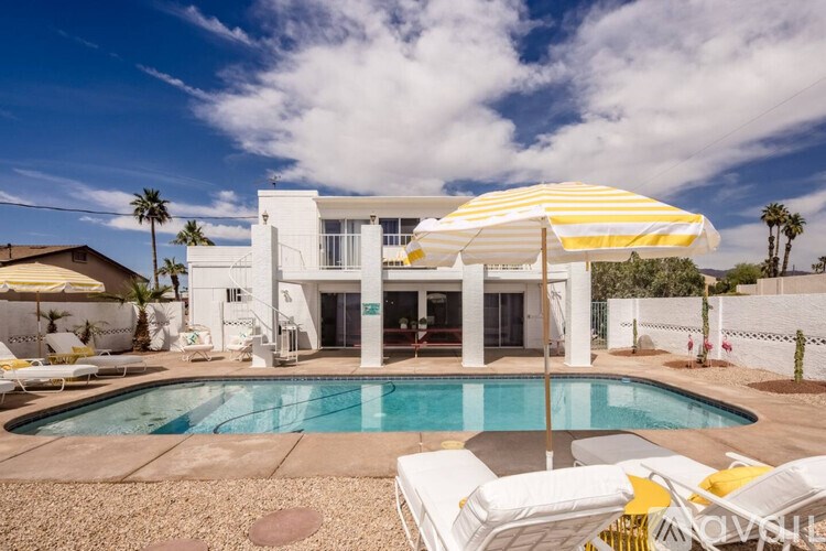 A white house with a pool in front.