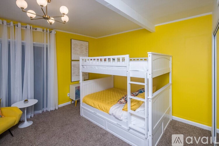 A room with a white bunk bed and a yellow sofa.