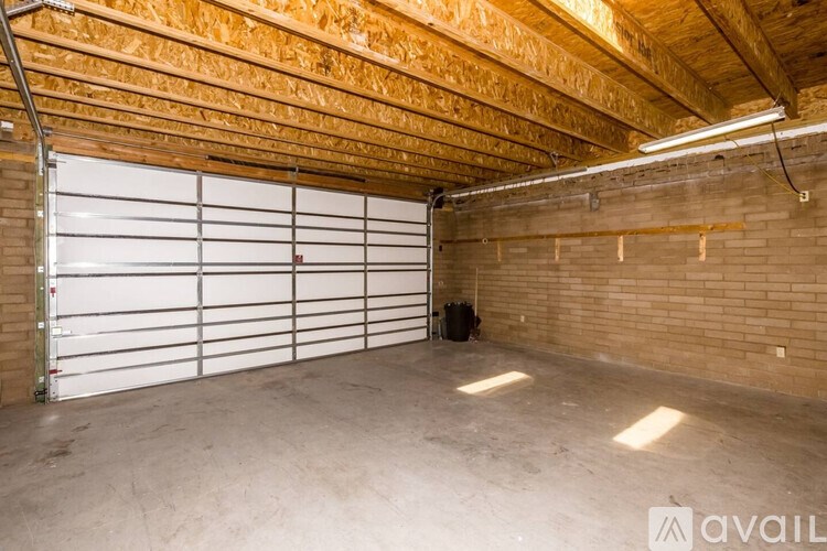 A spacious garage with a white roll-up door and wooden ceiling.