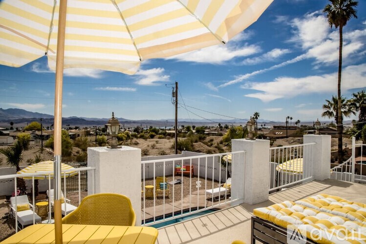 A patio with yellow chairs and umbrellas overlooking a pool and a mountain.