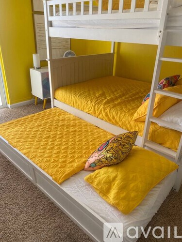 A white bunk bed with a yellow pillow on top.