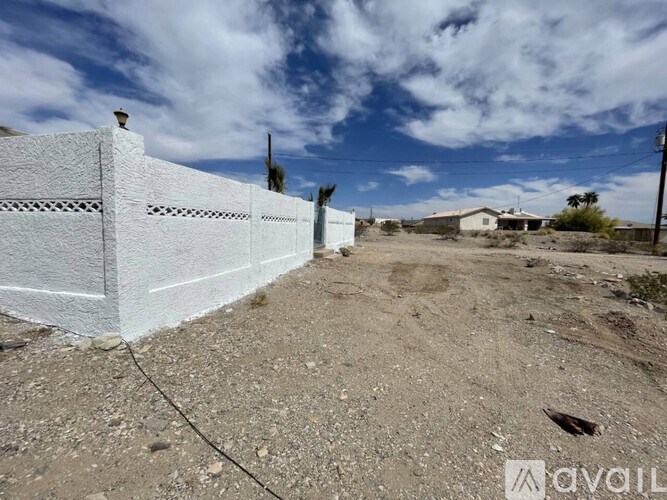 A white fence in a barren landscape under a blue sky.