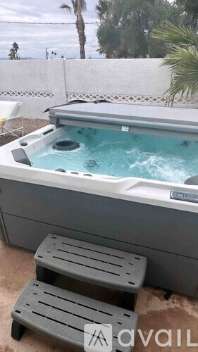 A hot tub with a grey cover and two grey steps in front of it.