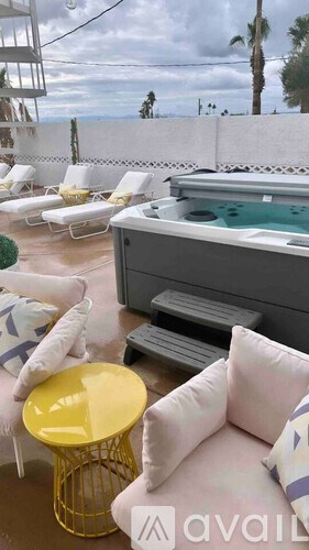 A patio with a hot tub, chairs, and a table.