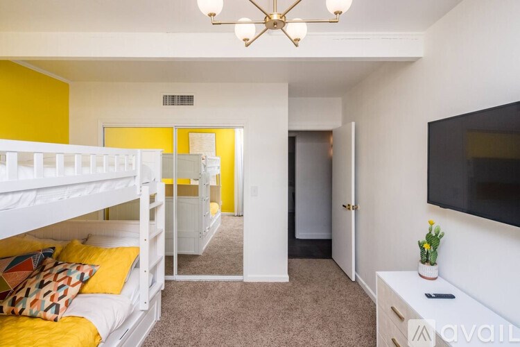 A room with white bunk beds and a yellow accent wall.